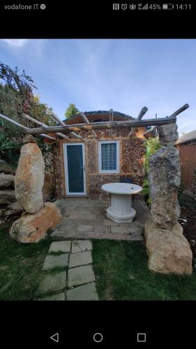 a stone house with a picnic table in the yard at Il Giardino dei Flintstones B&B in Cerveteri