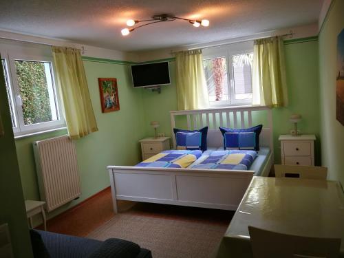 a bedroom with a bed with blue pillows and a tv at Gästezimmer Sieg in Rust