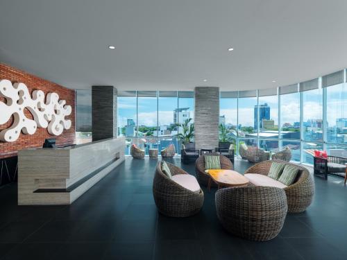 a lobby with chairs and tables and windows at Melia Makassar in Makassar