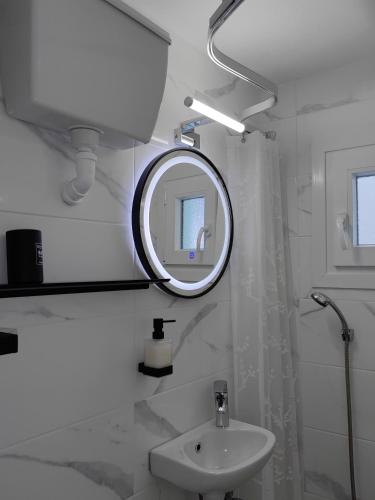 a white bathroom with a mirror and a sink at Little Kristi in Palaiókastron