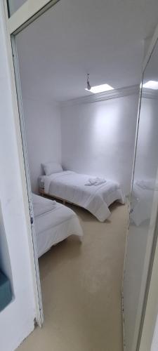two beds in a white room with a mirror at Villa NAIM in Marrakech