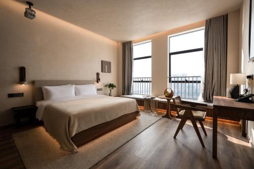 a bedroom with a bed and a desk and two windows at 大有观于All about Yu Hotel in Chongqing