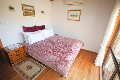 a bedroom with a bed with a red comforter at Clarendon Forest Retreat in Possum Brush