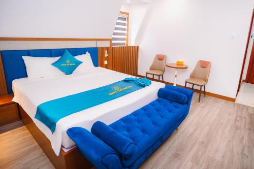 a bedroom with a large bed with a blue couch at Crystal Holiday Ha Long Hotel in Ha Long