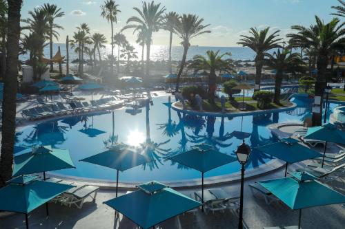 an overhead view of a pool with blue umbrellas at Riadh Palms- Resort & Spa in Sousse