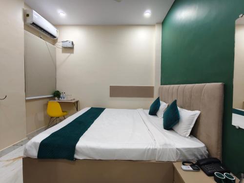 a bedroom with a large bed with a green wall at Shri Sundaram Residency by Clovetree in Varanasi