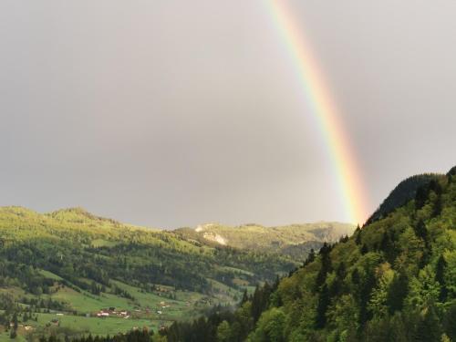 a rainbow over a valley with green hills at Casa Codrilor in Lacu Rosu