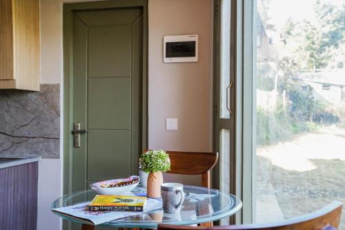 a glass table in a kitchen with a window at SaffronStays Edelweiss Estate Amore in Chaubattia