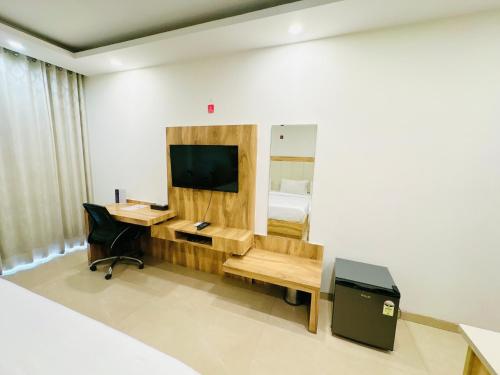 a bedroom with a bed and a desk with a television at Hotel Golf View Sakura & Suites in Gurgaon