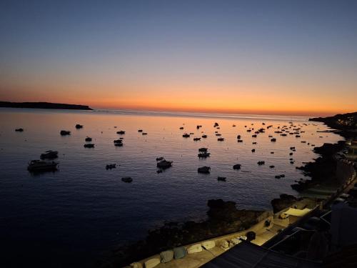 a group of boats in the water at sunset at Luxury Seafront Apartment with Panoramic Views- Ghadira, Mellieha Bay in Mellieħa