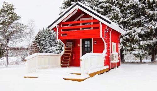 a red cabin in the snow with trees at Alanko Lodge in Tornio