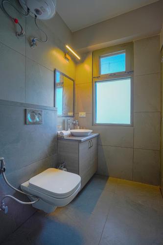 a bathroom with a toilet and a sink and a window at SaffronStays Edelweiss Estate Amore in Chaubattia