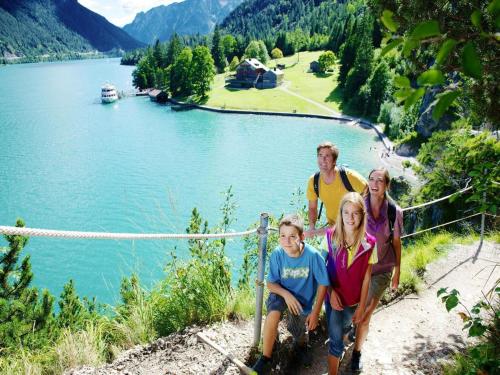 a group of people sitting on a fence near a lake at Apartment in Achenkirch with a garden in Achensee