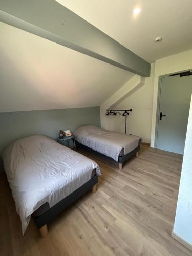 a bedroom with two beds and a hallway with a door at Gite Clé des Champs in Montenois