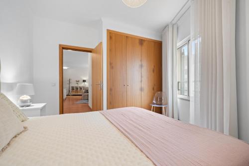 a white bedroom with a large bed and a hallway at Refúgio do Garajau by Atlântica in Caniço