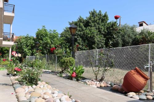 a garden with rocks and plants in front of a fence at Stratos Angels apartments in Pefkohori