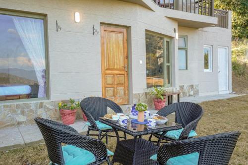a patio with a table and chairs and a house at SaffronStays Edelweiss Estate Amore in Chaubattia