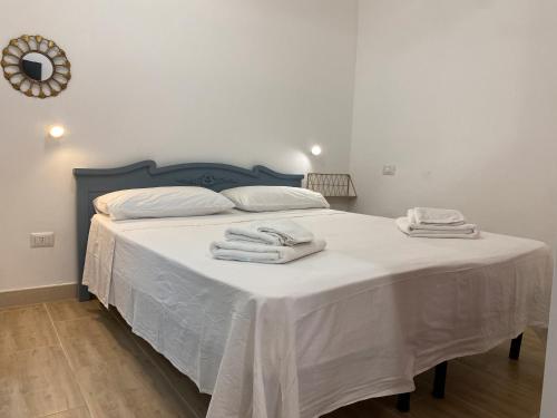 a bed with white sheets and towels on it at Isid'Oro Rooms - 100m from the sea in Sant'Isidoro