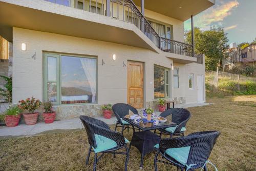 a patio with chairs and a table in front of a house at SaffronStays Edelweiss Estate Amore in Chaubattia