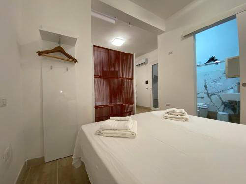 a white bedroom with two towels on a bed at Isid'Oro Rooms - 100m from the sea in Sant'Isidoro