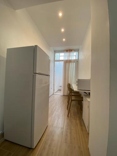 a white refrigerator in a kitchen with a desk at Isid'Oro Rooms - 100m from the sea in Sant'Isidoro