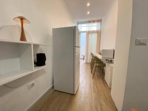 a white refrigerator in a kitchen with a table at Isid'Oro Rooms - 100m from the sea in Sant'Isidoro