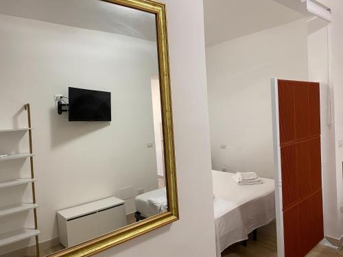 a mirror in a white room with a bed and a bed sqor at Isid'Oro Rooms - 100m from the sea in Sant'Isidoro