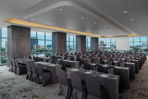 a large banquet hall with tables and chairs in a room with windows at Melia Makassar in Makassar