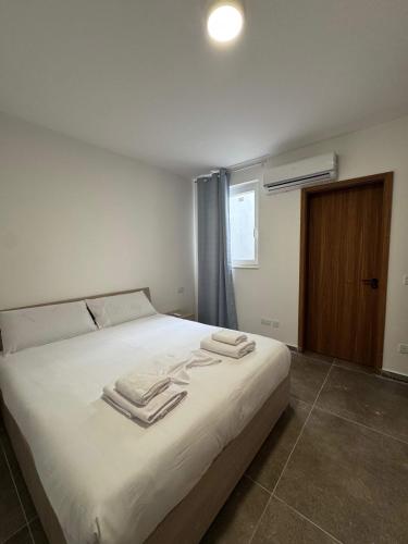 a bedroom with a white bed with towels on it at Serenity Escape 2 Bed with Patio in Taʼ Penza