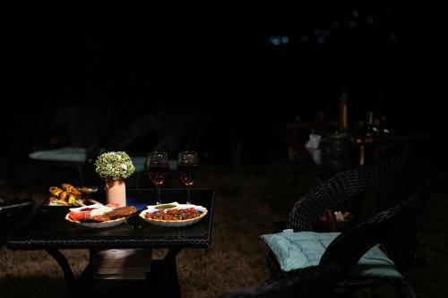 a table with two glasses of wine and food on it at SaffronStays Edelweiss Estate Amore in Chaubattia