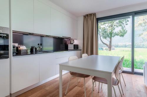 a white kitchen with a white table and chairs at Residenza Ticino by Quokka 360 - Modern Oasis near Bellinzona in Bellinzona