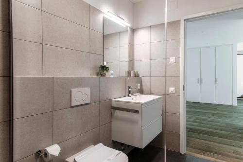 a bathroom with a toilet and a sink and a mirror at Residenza Ticino by Quokka 360 - Modern Oasis near Bellinzona in Bellinzona