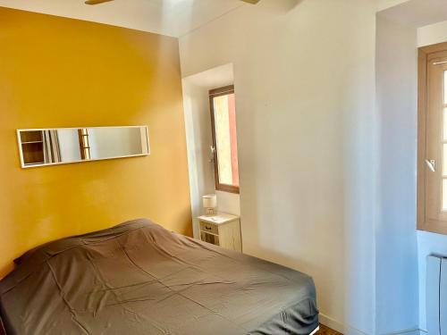 una camera con un letto e una parete gialla di Appartement centre historique de Grasse, capitale des parfums a Grasse