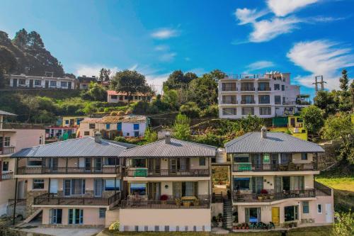 a group of houses on a hill with buildings at SaffronStays Edelweiss Estate Amore in Chaubattia