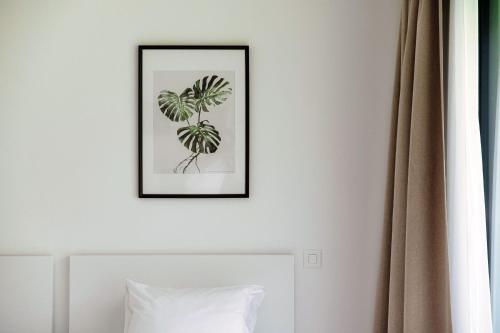 a picture of a plant on a wall above a bed at Residenza Ticino by Quokka 360 - Modern Oasis near Bellinzona in Bellinzona