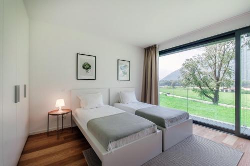 two beds in a room with a large window at Residenza Ticino by Quokka 360 - Modern Oasis near Bellinzona in Bellinzona