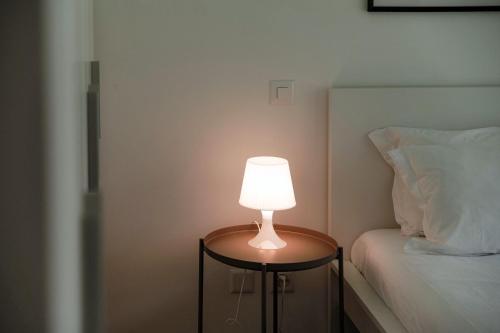a lamp on a table next to a bed at Residenza Ticino by Quokka 360 - Modern Oasis near Bellinzona in Bellinzona