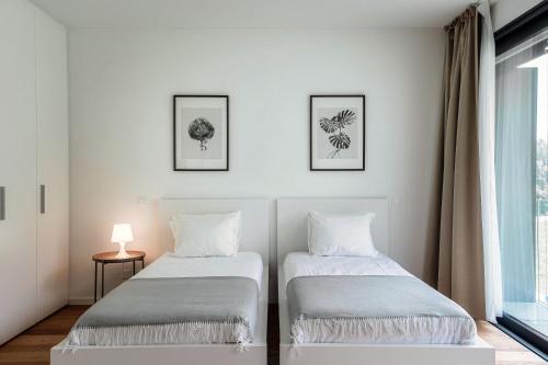 two beds in a room with white walls and a window at Residenza Ticino by Quokka 360 - Modern Oasis near Bellinzona in Bellinzona