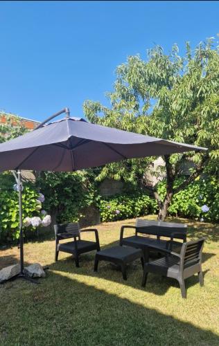two benches and an umbrella in the grass at House of Santiago de Compostelle 