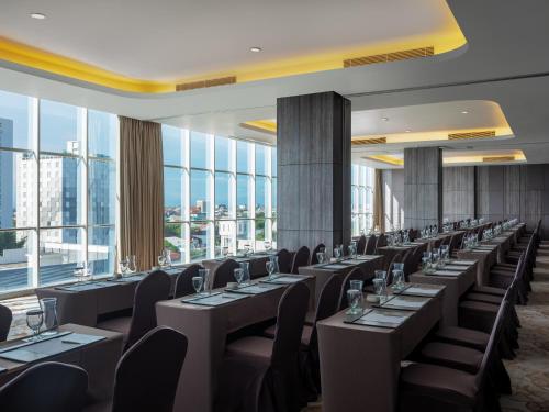 a row of tables and chairs in a room with windows at Melia Makassar in Makassar