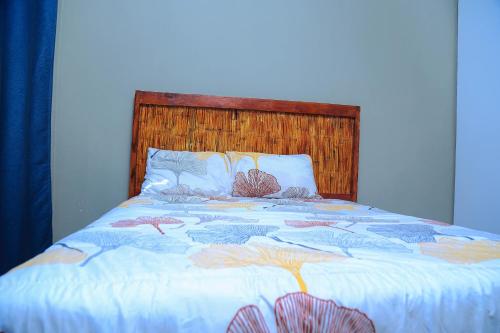 a large bed with a wooden headboard at Forest Views Haven in Solwezi