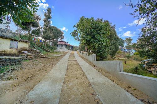 an empty dirt road with trees on the side at SaffronStays Edelweiss Estate Amore in Chaubattia