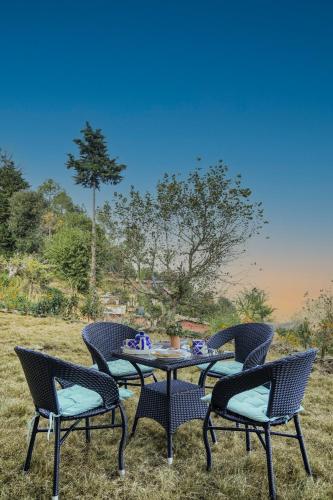 a table and chairs sitting on top of a field at SaffronStays Edelweiss Estate Amore in Chaubattia