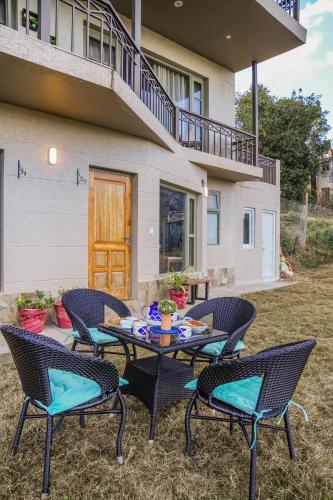 a patio with chairs and a table in front of a house at SaffronStays Edelweiss Estate Amore in Chaubattia