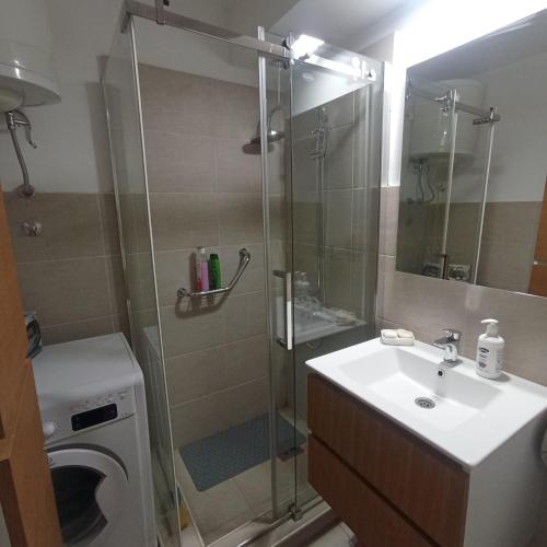 a bathroom with a shower and a sink and a washing machine at Apartman Icić in Pirot