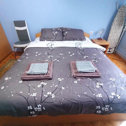 a bed with a black blanket with white flowers on it at Apartman Icić in Pirot