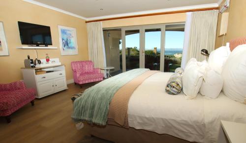 a hotel room with a bed and a tv and a window at On The Cliff Guest House in Hermanus