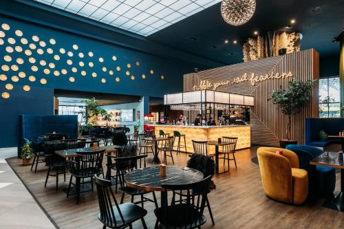 un restaurant avec des tables et des chaises et un bar dans l'établissement Naumi Hotel Auckland Airport, à Auckland