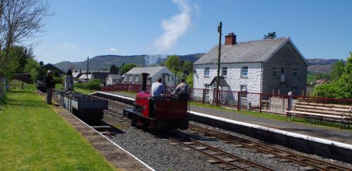 two people on a small train on the tracks at Bwch yn Uchaf B&B in Llanuwchllyn