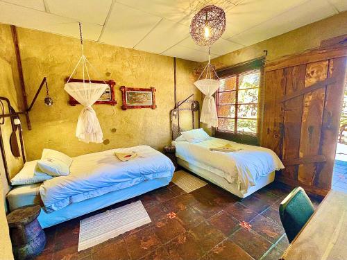 a bedroom with two beds and a chandelier at Roy's Rest Camp in Groutfontein